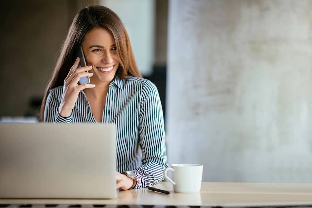 Frau telefoniert an ihrem Arbeitsplatz mit Smartphone | Mobile as a Service | ACP - IT for innovators.