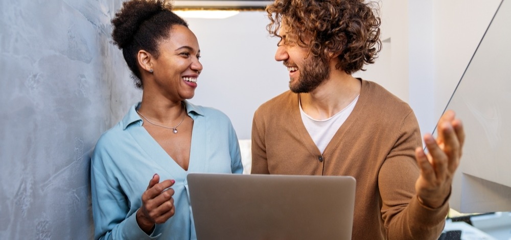 Zwei Mitarbeitende sprechen mit Laptop - shutterstock_2676415819