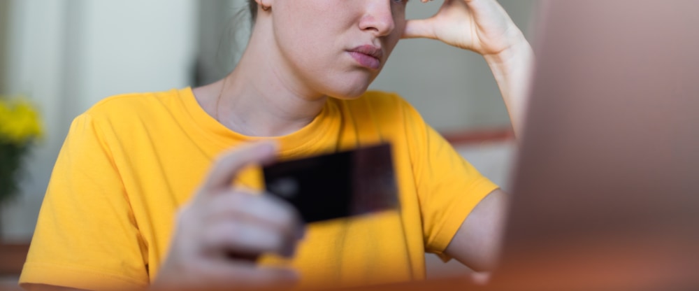 Dame sitzt vor Laptop wegen eines Cyber Angriffs und will zahlen. | ACP - IT for innovators.