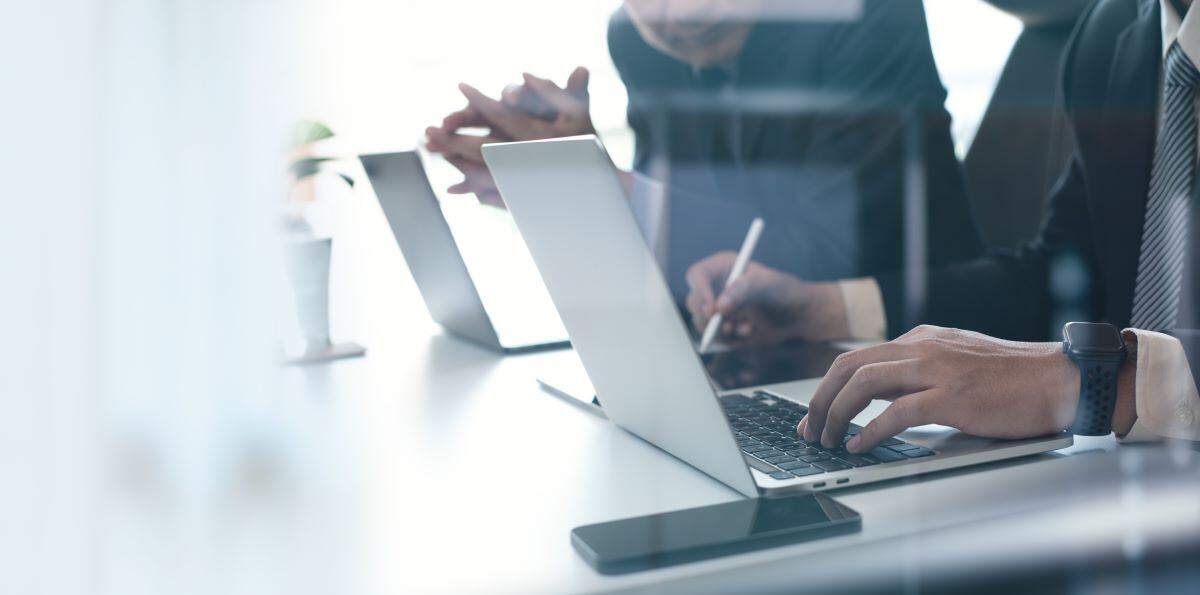 Zwei Personen vor Laptops - shutterstock_2476549551