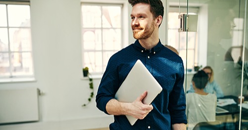 zufriedener Mitarbeiter mit Laptop in der Hand